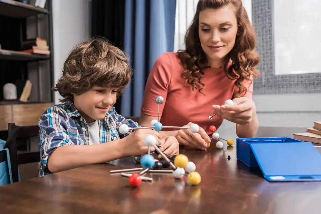 young mother and preteen son playing with atoms model at home